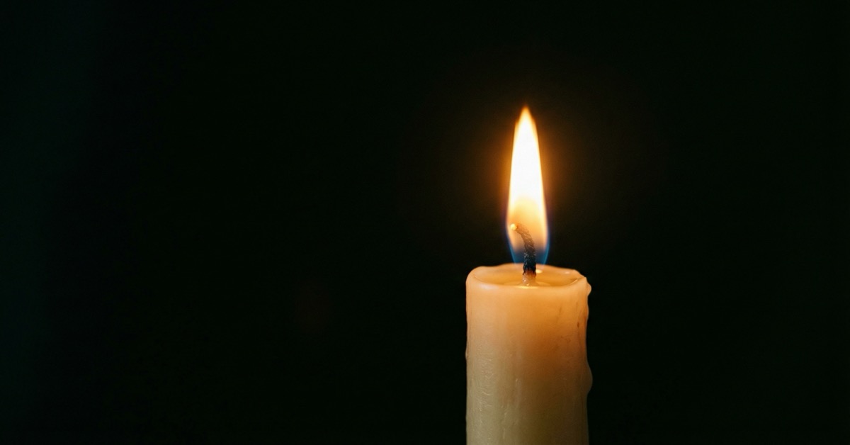 A single candle flame burning steadily against a dark background in warm golden light.