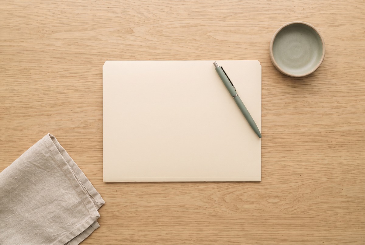 A blank cream document folder and a sage pen laid out on a light oak desk, ready for the formation paperwork and EIN.
